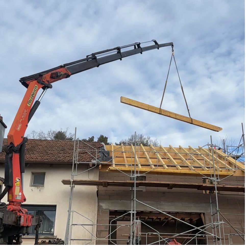 Levage d'une panne à la grue lors de la reconstruction d'une toiture dans les Vosges
